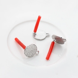 Close-up of textured round silver earring posts for DIY jewelry making in ceramic tray