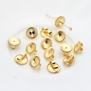 Macro shot of 14K gold-filled sunflower-shaped earring backs on a ceramic plate
