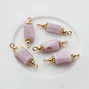Detail of five cylindrical pink natural stone charms with gold-plated double eyelets