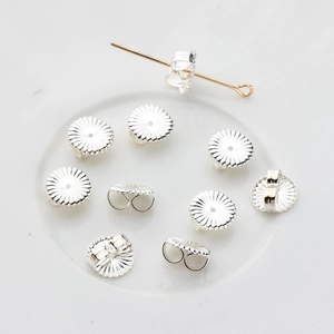Close-up of 925 sterling silver flower ear nuts showing detailed petal texture on white tray