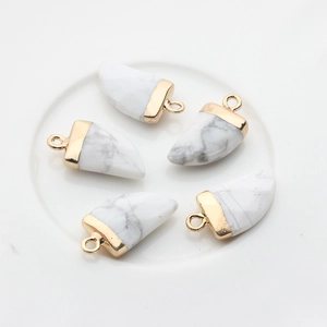 Detail van vijf witte wolfstand stenen hangers met gouden kappen op keramiek