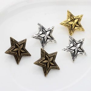 Vintage alloy star-shaped metal pendants in bronze, silver, and gold on a white ceramic plate