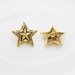 Detailed view showing both sides of a vintage star-shaped metal button in antique gold