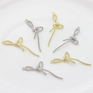 Vue détaillée de pendentifs nœuds en métal doré et argenté avec texture de corde