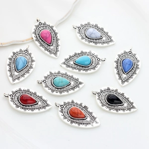 Set of retro alloy teardrop pendants with colorful resin stones on a white plate