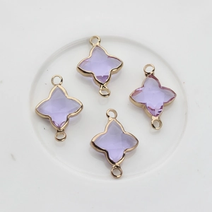 Vue macro de quatre pendentifs trèfle violets avec monture dorée et doubles boucles