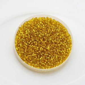 Macro detail of 2mm bright yellow glass seed beads for DIY jewelry making and craft projects