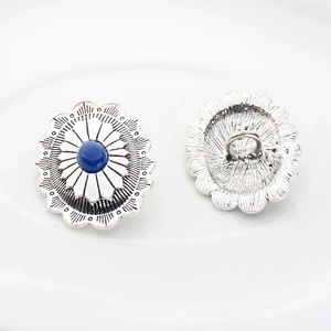 Dettaglio dei bottoni vintage argento con motivi floreali e centro in resina blu