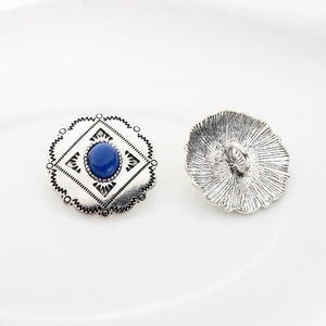 Detail of vintage silver alloy button with blue oval stone and wave edge texture