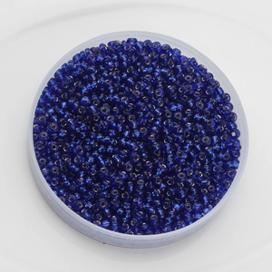 Close-up of 2mm dark blue glass seed beads in a clear round box for DIY jewelry making