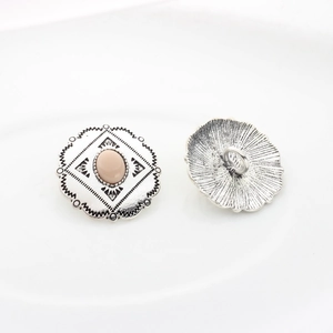 Macro detail of vintage silver alloy buttons with pink resin gemstone and floral lace edge