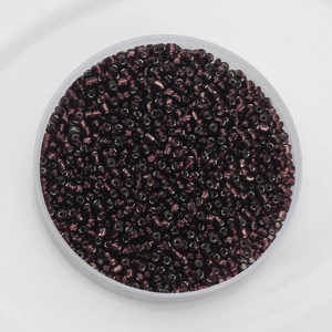 Top view of 2mm dark purple glass seed beads with metallic luster in a transparent tray