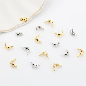 Macro shot of gold and silver jewelry end crimp beads on white ceramic tray