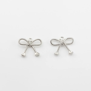 Detailed view of silver bow-shaped alloy pendants with textured twisted rope pattern design