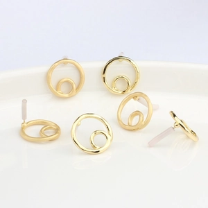 Boucles d'oreilles cercles dorés géométriques avec texture martelée sur plateau blanc