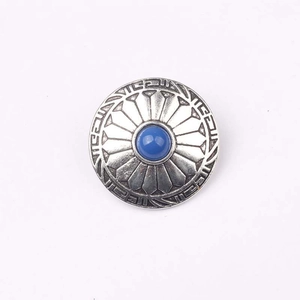 Detailed view of vintage silver zinc alloy button with engraved patterns and blue bead