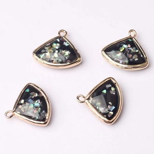 Macro shot of fan-shaped glass pendants with gold metal frames and iridescent details