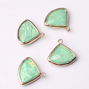 Close-up of four light green fan-shaped crystal glass pendants with gold metal frames