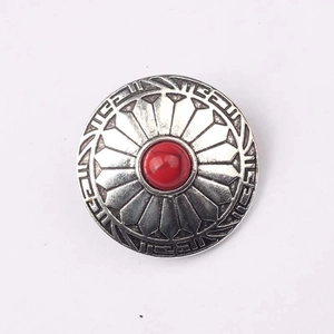 Macro view of vintage zinc alloy button with red stone inlay and tribal flower patterns