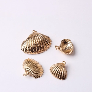 Vue détaillée de pendentifs coquillage dorés avec des rayures radiales et un anneau de suspension