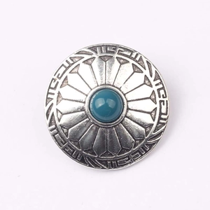 Detail of vintage zinc alloy button with turquoise bead and sunburst tribal engraving