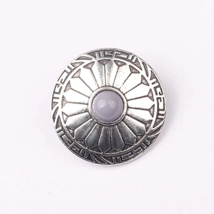 Detail of vintage zinc alloy button with engraved patterns and a grey gemstone center