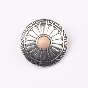 Macro detail of vintage zinc alloy button with pink resin stone and floral engraving