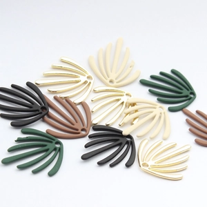 Macro view of geometric seaweed leaf charms in assorted matte and gold finishes