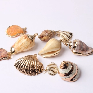 Coquillages naturels bohèmes avec bords plaqués or et anneaux de suspension sur fond blanc