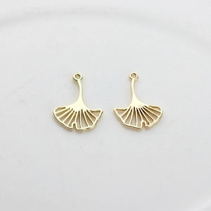 Detailed view of two gold-plated hollow ginkgo leaf charms for DIY jewelry making