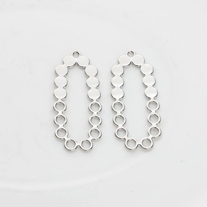 Macro detail of silver-tone hollow oval pendant with dot pattern for DIY jewelry making