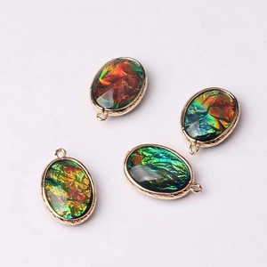 Colorful oval glass crystal pendants with gold engraved metal frames and glitter details