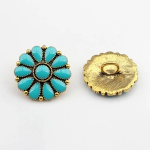 Détail d'un bouton fleur vintage avec pierres turquoise et bordure perlée dorée