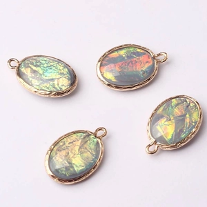 Detail of four oval aurora crystal pendants with wavy gold metal frames and vibrant colors