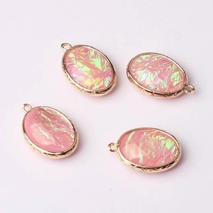Macro shot of 4 oval pink translucent pendants with iridescent glitter and gold frames