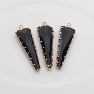 Detalle de tres colgantes triangulares negros facetados con borde dorado para joyería DIY
