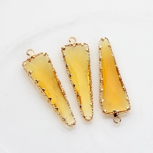 Detalle macro de colgantes triangulares de cristal amarillo con bordes dorados