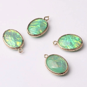 Macro detail of oval green iridescent pendants with textured rose gold metal frames
