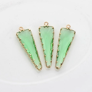 Detalle de tres colgantes triangulares de vidrio facetado verde claro con bordes dorados