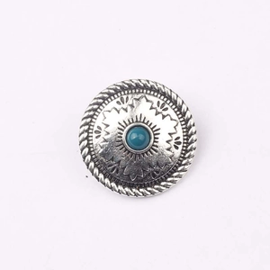 Dettaglio di un bottone concho vintage in argento con motivo solare e pietra turchese