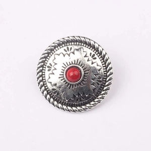 Dettaglio di bottone concho vintage argento con perla rossa e motivi tribali