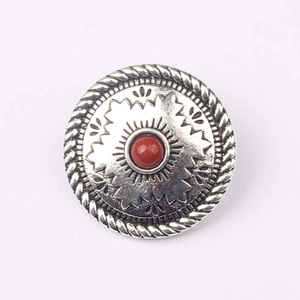 Dettaglio di bottone concho vintage in argento con motivo a raggiera e pietra rossa