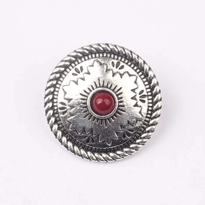 Dettaglio di bottone vintage in lega d'argento con pietra rossa e motivi floreali