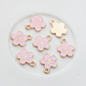 Dettaglio di ciondoli a fiore di ciliegio in smalto rosa e oro per gioielleria fai-da-te
