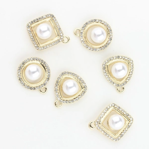 Detailed view of alloy jewelry charms with faux pearls and rhinestones in gold setting