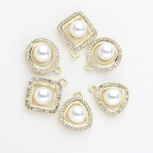 Detail of DIY jewelry charms with gold plating, rhinestones, and white pearls