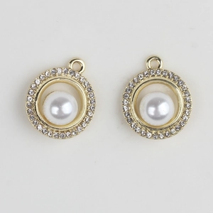 Detailed view of golden round pendant with inlaid rhinestones and a central white pearl