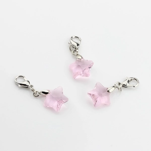 Macro shot of three pink crystal star charms with silver lobster clasps on white background