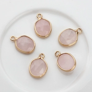 Detalle de cinco colgantes ovalados de piedra rosa facetada con borde dorado para joyería