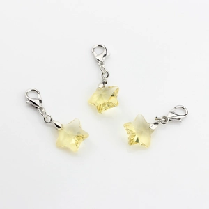 Detailed view of three faceted yellow crystal star pendants with lobster clasps for bags